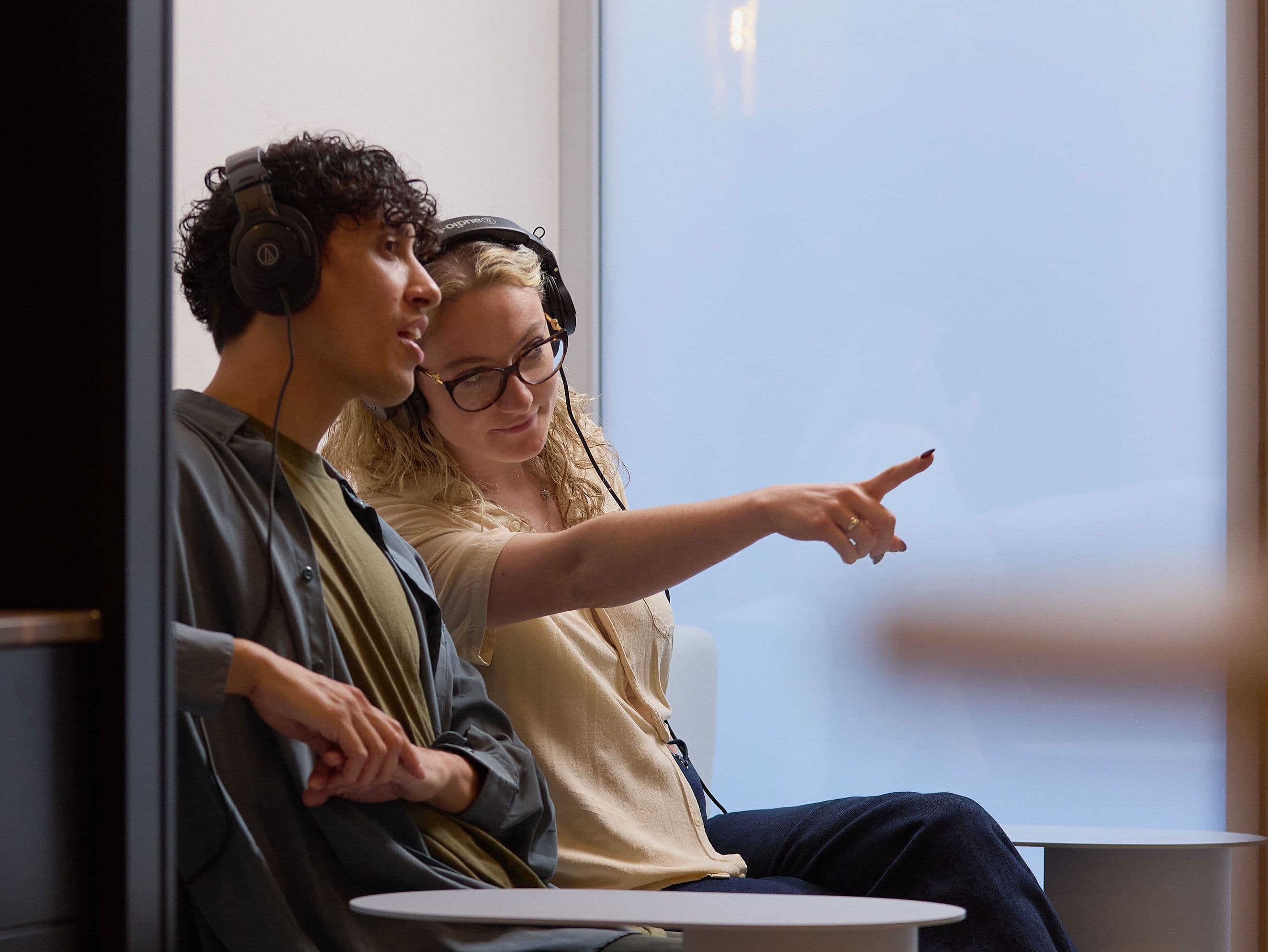 A man and woman sitting in the viewing area and woman pointing to something